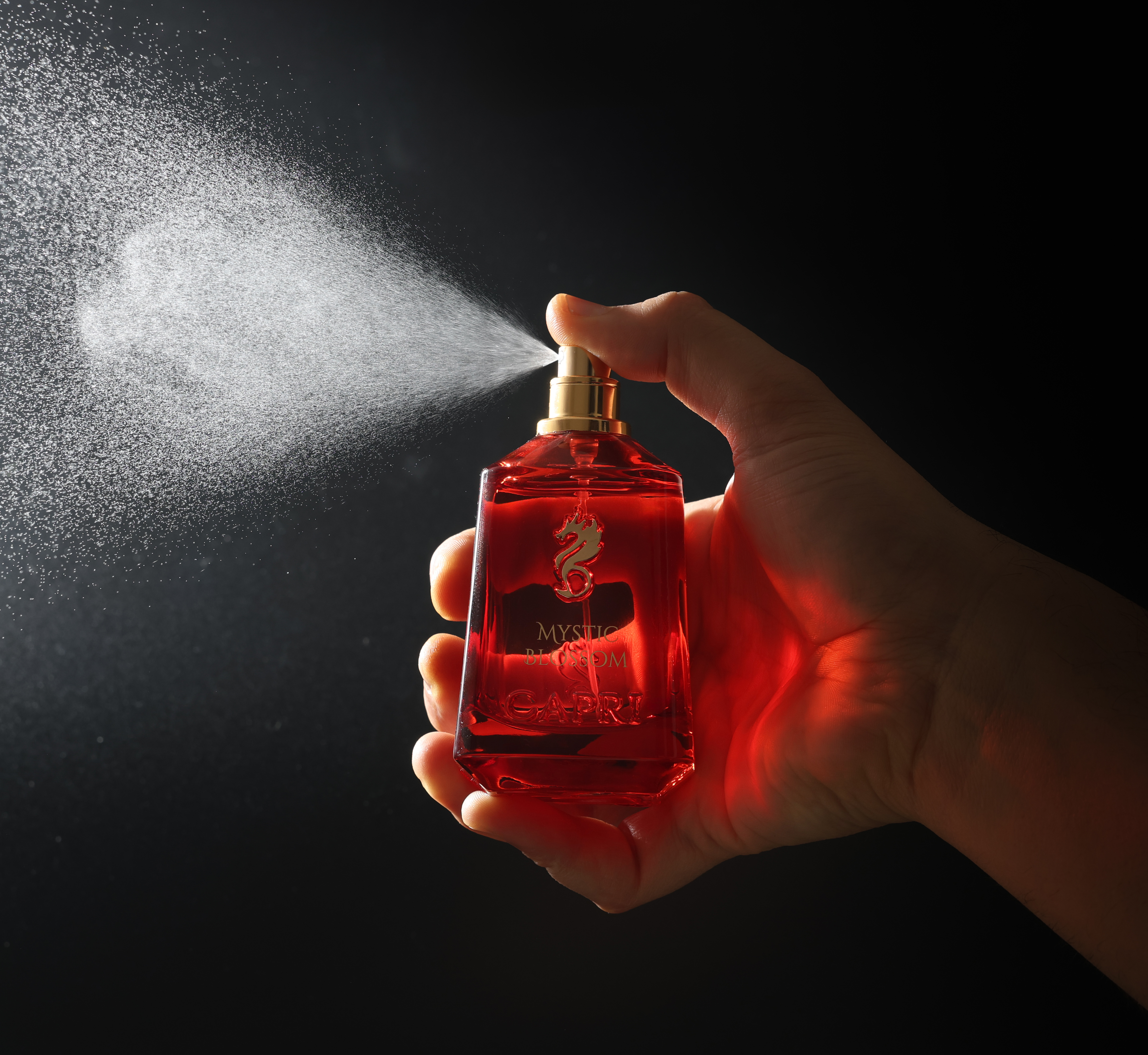 "يد ترش عطر فاخر من زجاجة حمراء أنيقة باسم Mystic Blossom من Capri، بخ خلفية سوداء بإضاءة درامية"
